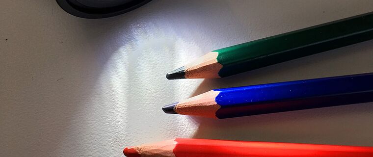 Verschiedenfarbige Buntstifte mit Taschenlampe angestrahlt